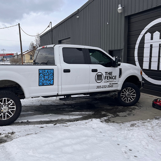 The Fence Company truck wrapped with company branding parked outside the Fence Company work shop